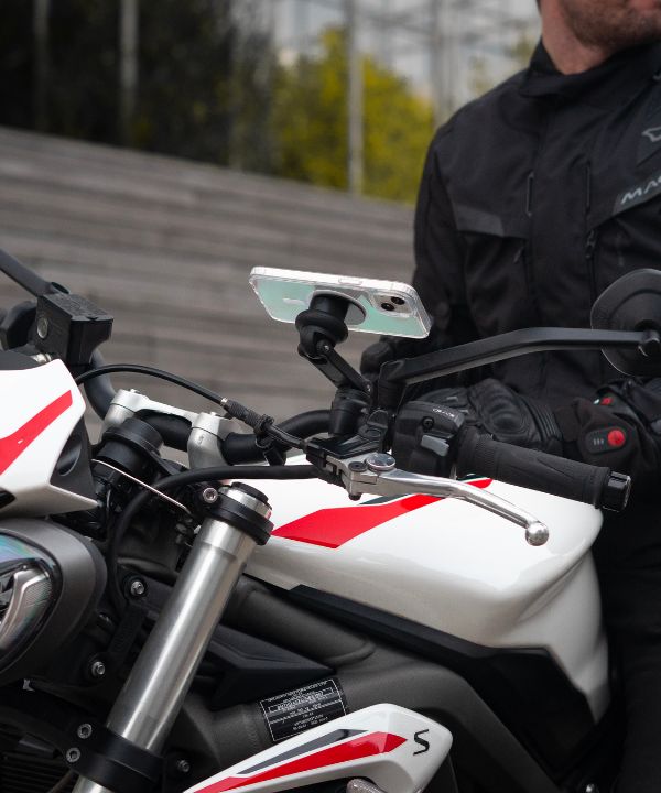 Un motard sur la route regardant son rétroviseur pour anticiper la circulation autour de lui. Une scène qui reflète l'importance d’une vigilance constante en milieu urbain.