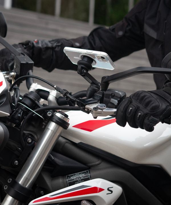 Un feu rouge avec un motard prêt à redémarrer, illustrant la nécessité de maîtriser ses départs. La posture du motard montre sa concentration avant de reprendre la route.