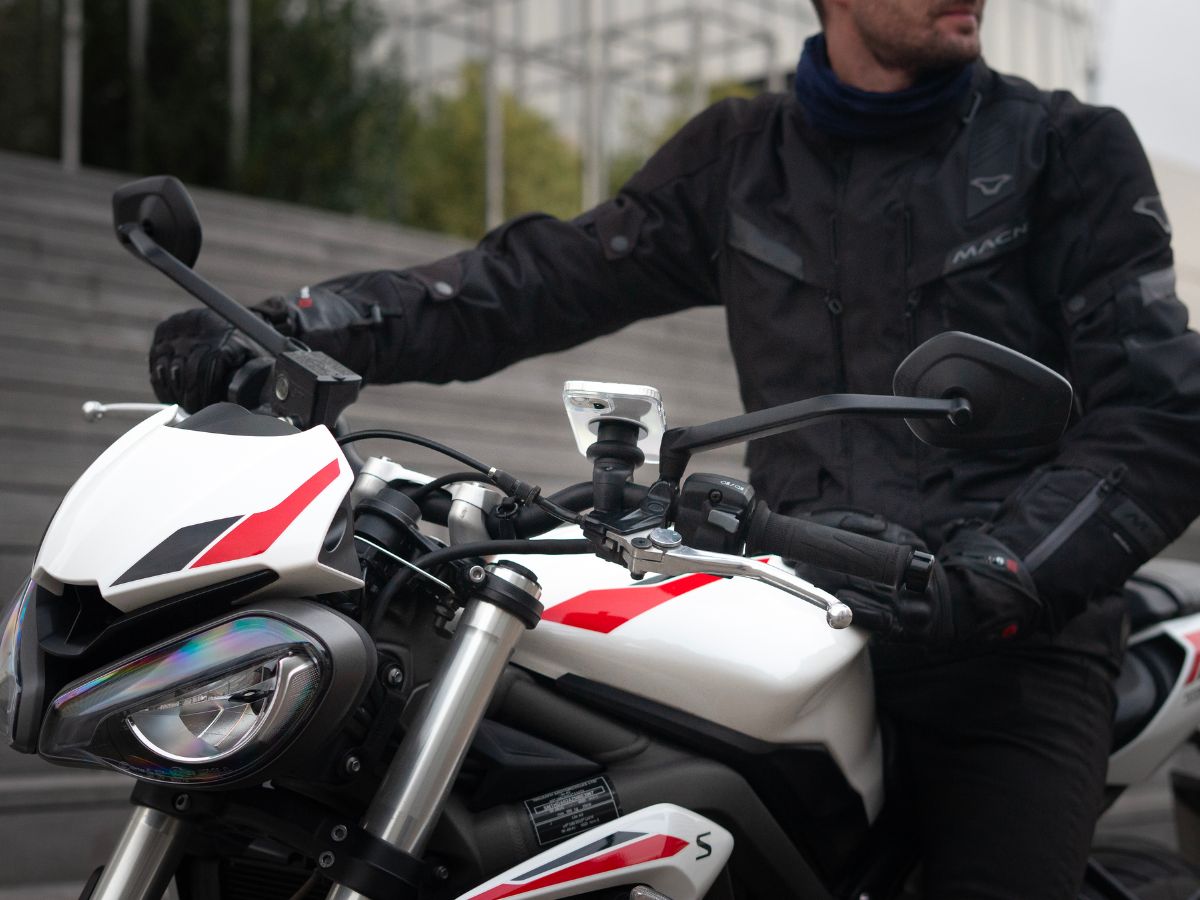 Un motard portant une veste réfléchissante avec son feu allumé, illustrant l'importance d’être visible. L’image insiste sur l’équipement de sécurité pour réduire les risques d’accident.