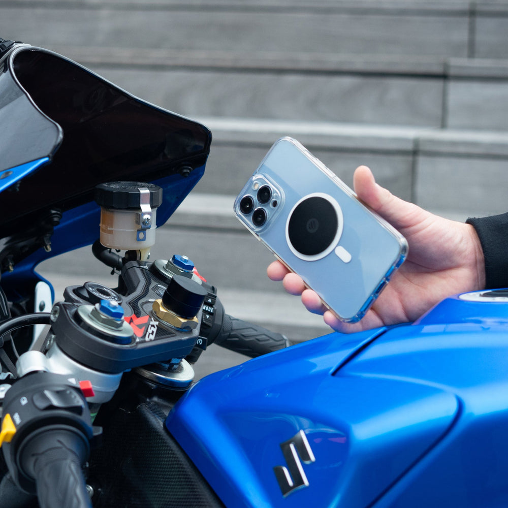 Smartphone avec plaque métal Shapeheart tenu devant le guidon d'une moto sportive